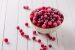 Frozen cranberry in bowl on white wooden background. Selective focus.